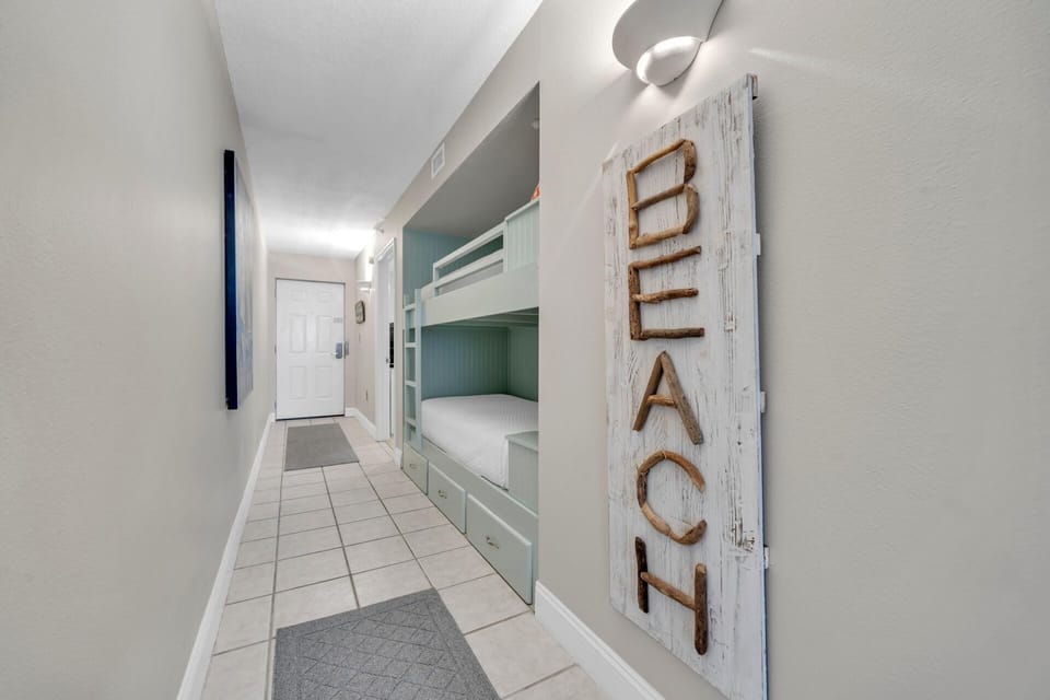 You'll love the custom turquoise bunk beds with built-in storage, perfect for families. The charming beach sign adds coastal charm to your home-away-from-home.