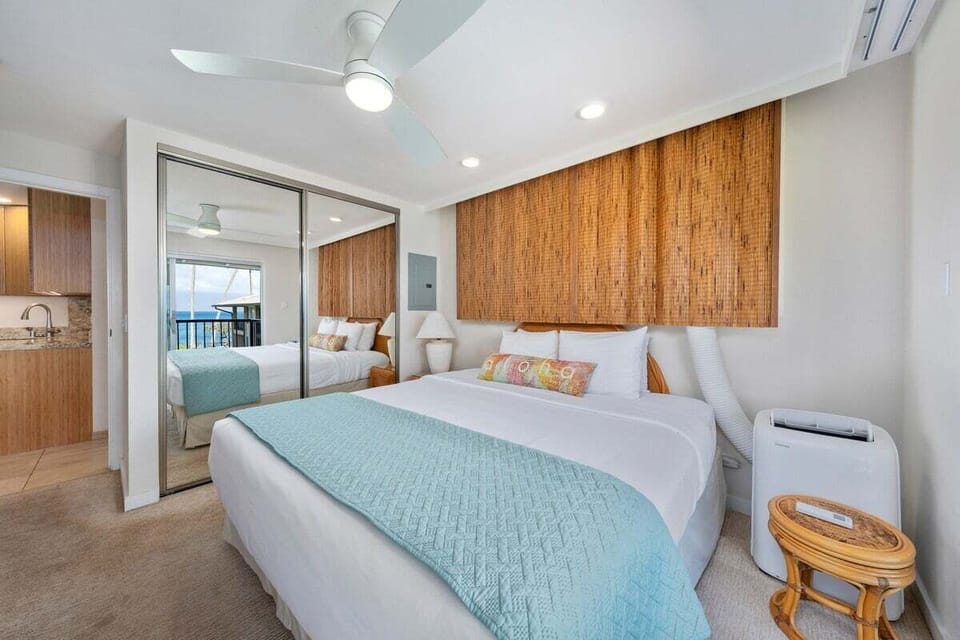 Spacious bedroom with mirrored closets — ceiling fan, AC, and ocean views for comfort and style.