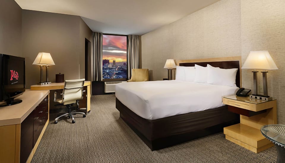 Relax into crisp linens with skyline views and warm lighting.