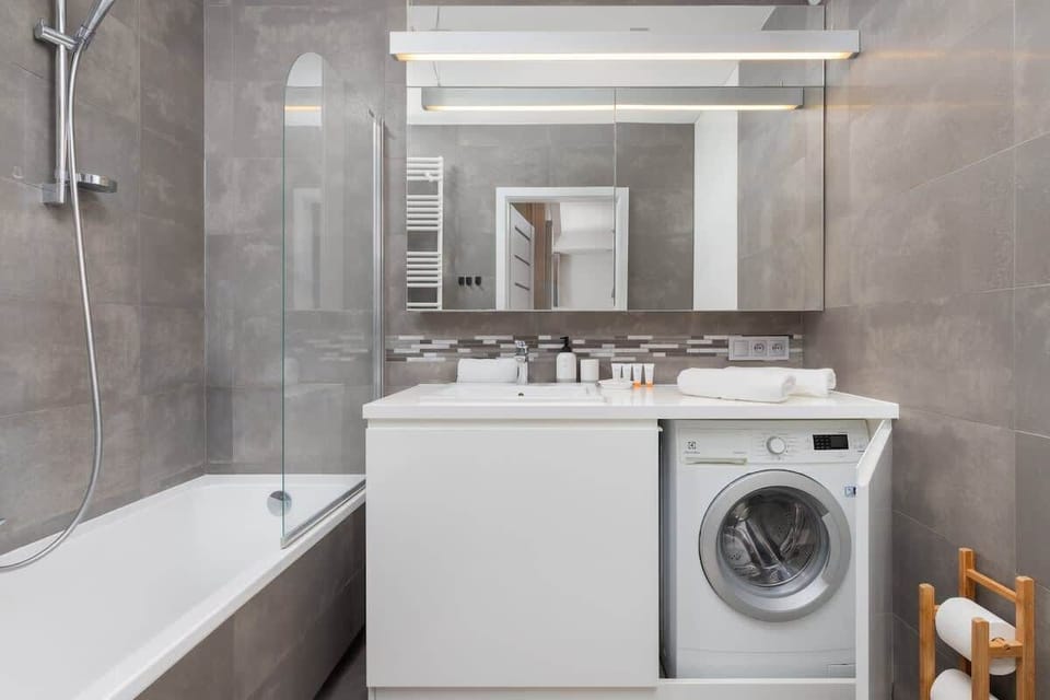 Bathroom with bathtub and washer – Relax after a long day and take advantage of the in-unit laundry.

