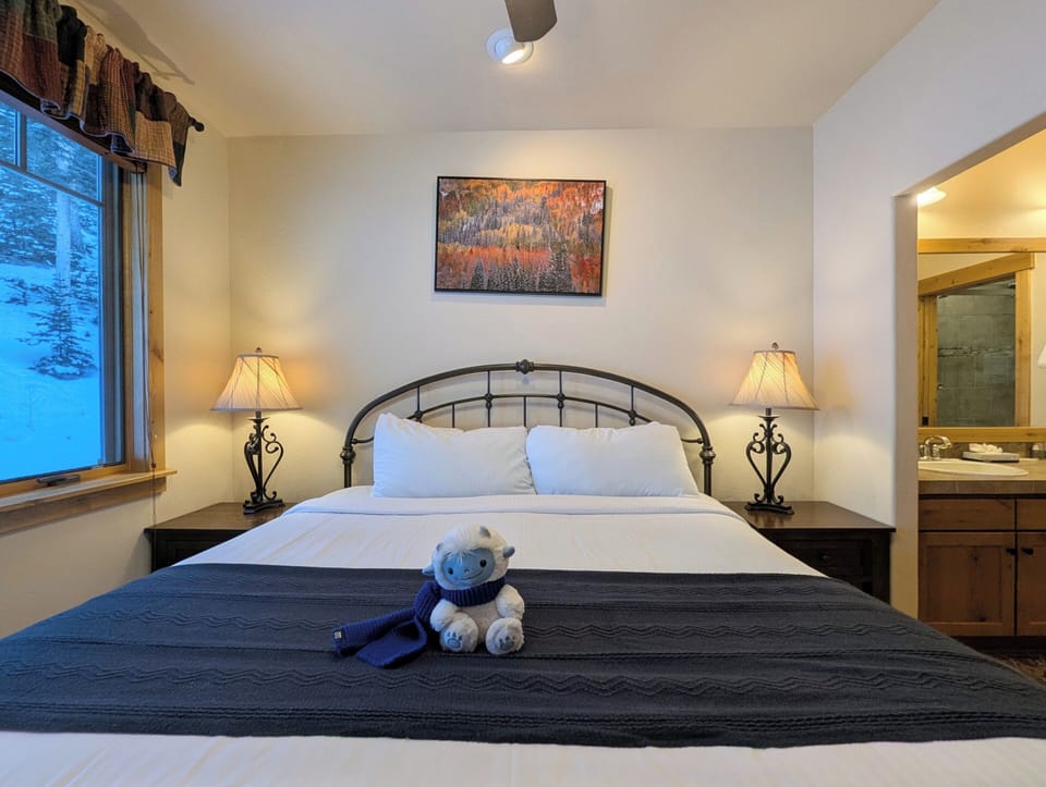 Your cozy bedroom awaits with plush bedding, warm lighting, and thoughtful touches creating the perfect retreat after mountain adventures.