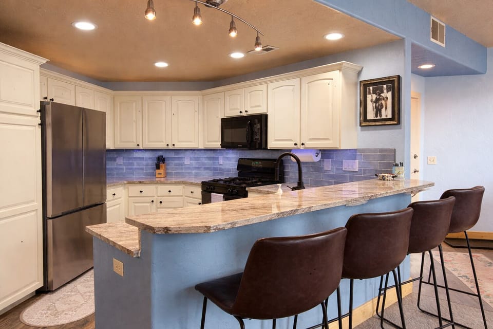 Well-appointed kitchen featuring granite countertops, stainless steel appliances, and bar seating for casual meals.