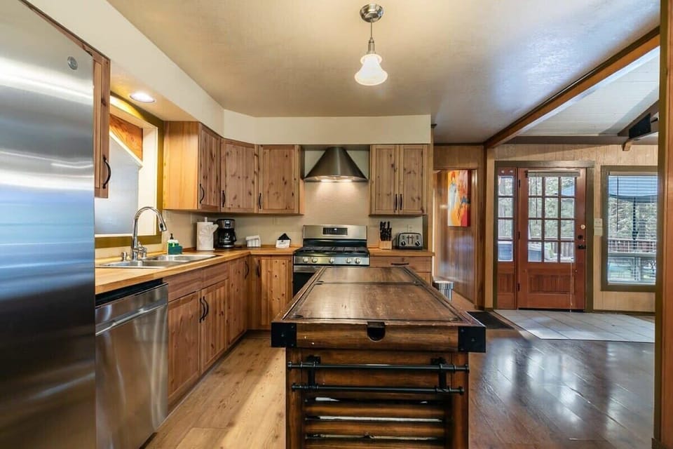 The well-equipped kitchen features beautiful wood cabinets, stainless steel appliances, a kitchen island providing extra space for meal prep, and a kitchen bar with 4 bar stools.