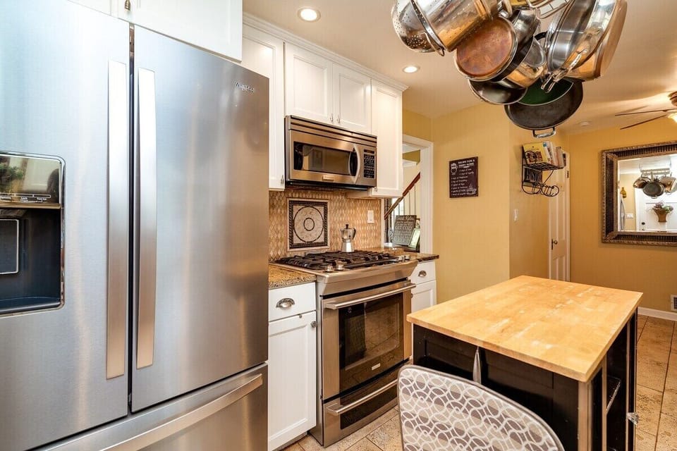This fully equipped kitchen includes a modern refrigerator with water/ice dispenser, gas cooktop, convection oven, and microwave—plus a central island and all the essentials for extended stays or home-cooked meals.