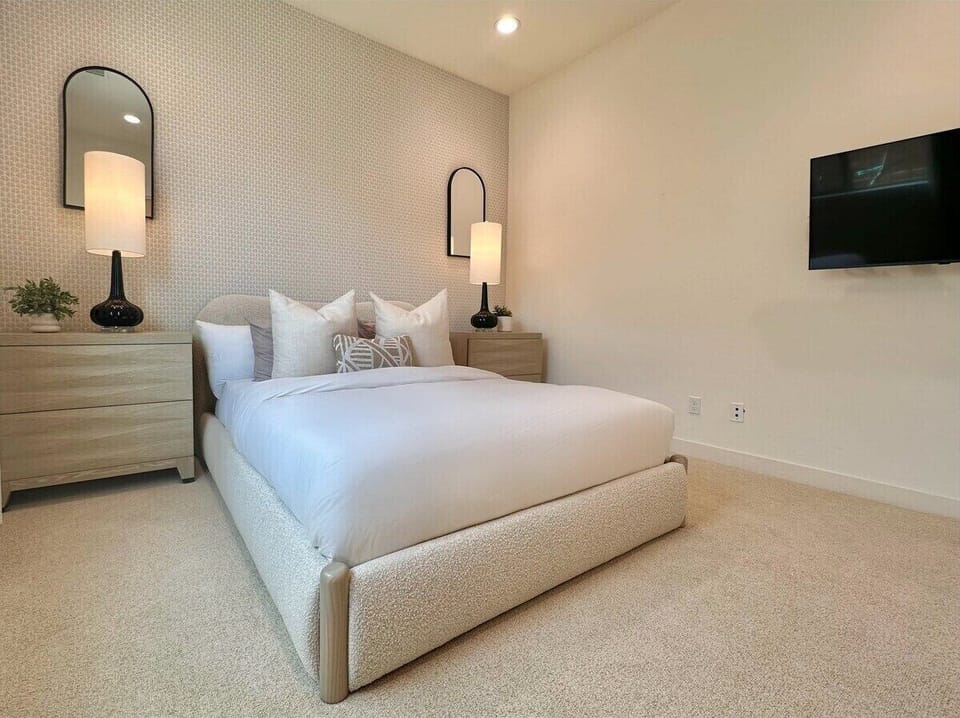 Third bedroom with upholstered platform bed—sconces free up nightstand space for books and coffee.