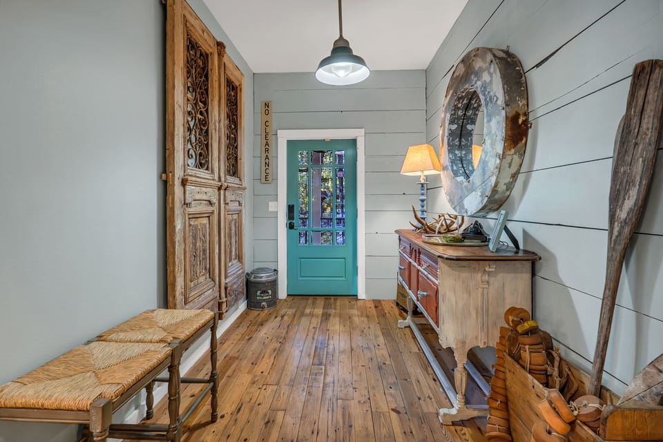 The entryway at the front door showcases solid antique wooden doors and reimagined rusty mirror.