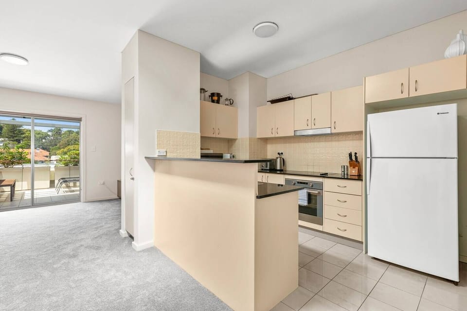 The kitchen features an induction cooktop, a double sink, dishwasher, an oven, and a microwave oven.
