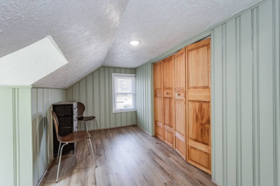 Nestled on the second floor, this charming bedroom boasts two twin beds, a seating area, and a cape cod ceiling for a unique and cozy vibe. Watch your favorite shows on the flat-screen Roku TV before drifting off to sleep!