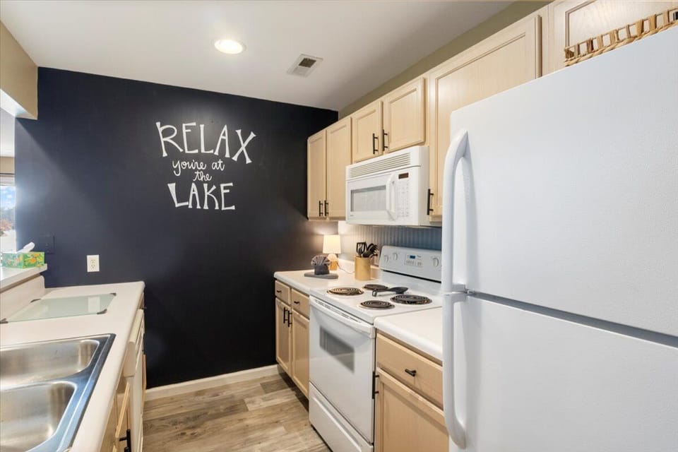 The galley kitchen offers white appliances, ample cabinets, and practical counter space for meal preparation.