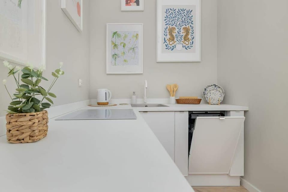 A final kitchen detail: a small plant on a white countertop, framed by decorative items and wall art.






