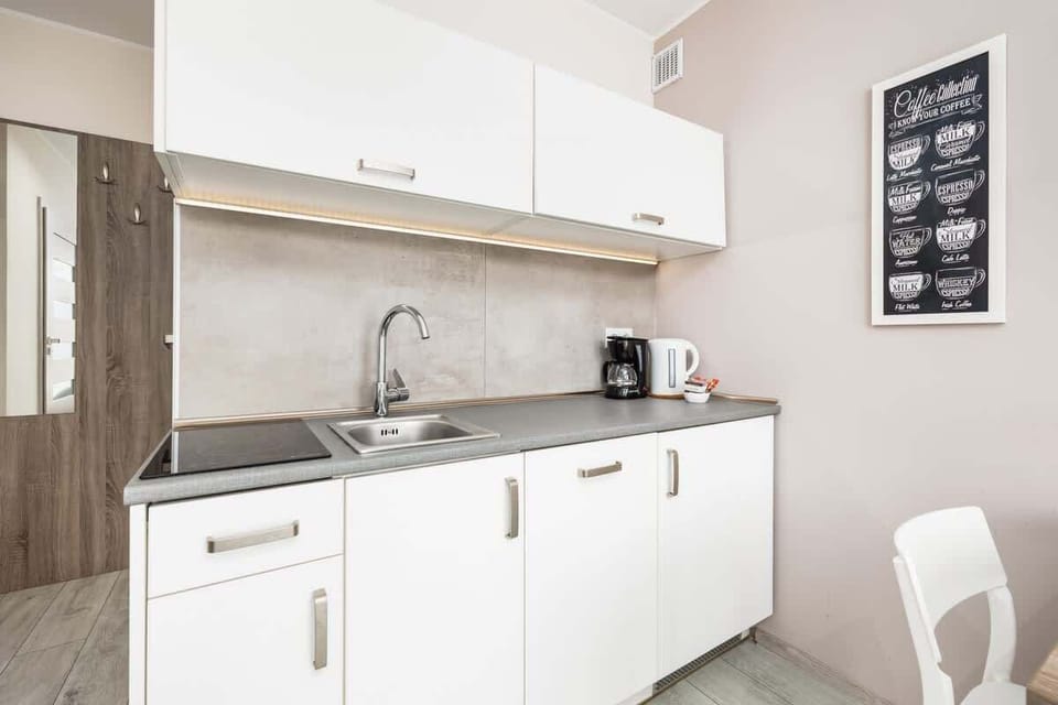 A compact kitchen with white cabinets, wooden shelves, and modern appliances.

