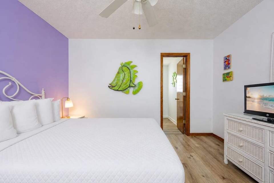 This bedroom features a bright, inviting atmosphere with a playful fish wall art and a TV for entertainment