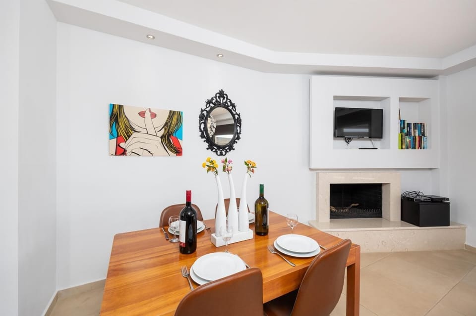 Open-plan living room with sofa, dining area, kitchen, ornamental fireplace, A/C, WiFi internet, and satellite TV