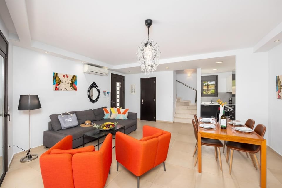 Open-plan living room with sofa, dining area, kitchen, ornamental fireplace, A/C, WiFi internet, and satellite TV
