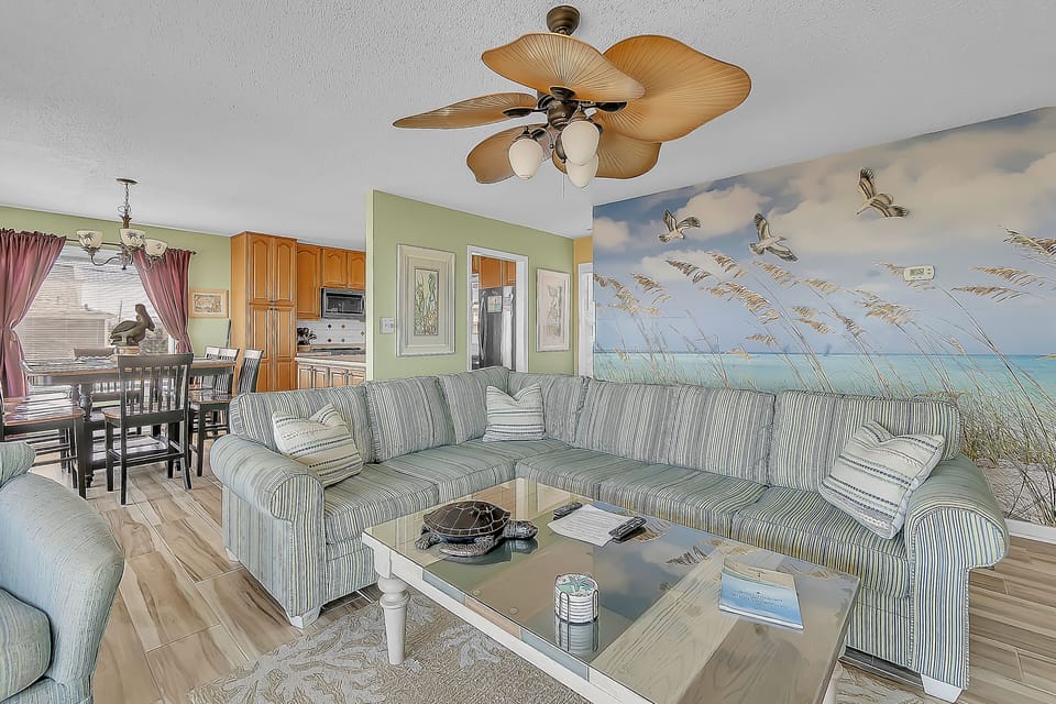 Unwind in your coastal retreat with striped sofas and a stunning beach mural that brings ocean breezes indoors.