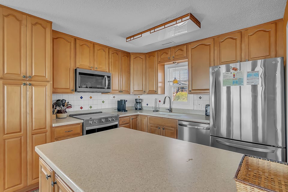 Your fully equipped kitchen features warm wood cabinets, stainless steel appliances, and plenty of counter space for preparing delicious meals during your stay.