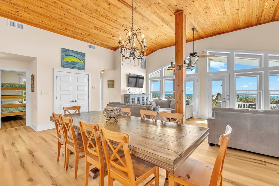 Gather around the rustic dining table where warm wood meets coastal charm, creating the perfect space for memorable meals together.