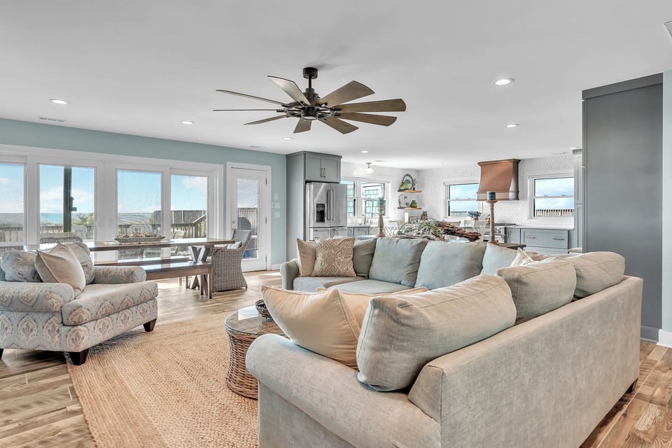 Sink into plush coastal sofas while ocean breezes flow through your open-concept living space, where kitchen, dining and relaxation blend seamlessly.