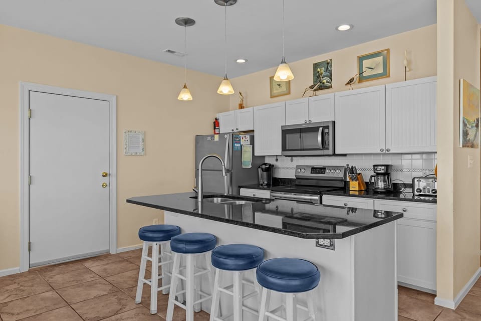 Your fully equipped kitchen awaits with granite counters, stainless appliances, and bar seating perfect for morning coffee or casual meals.