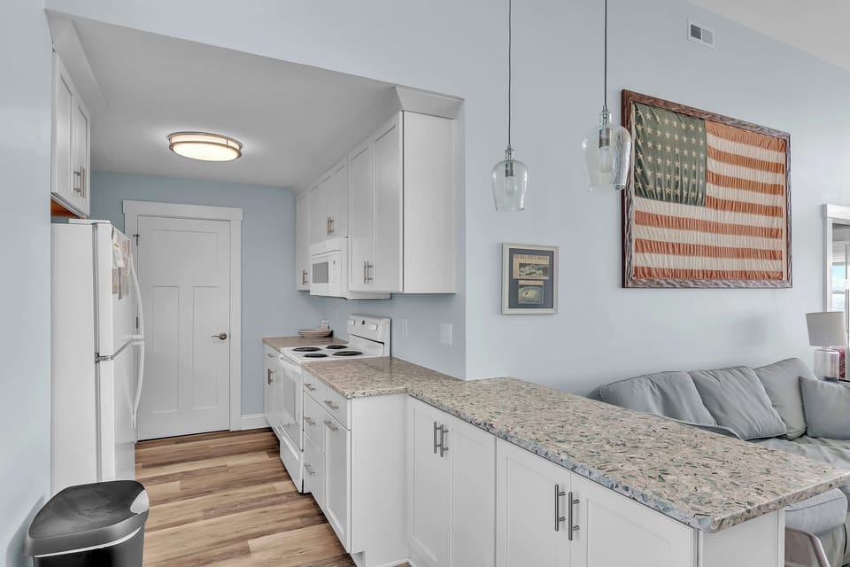 Your fully-equipped galley kitchen features granite countertops, white cabinets, and everything you need to create delicious meals during your stay.