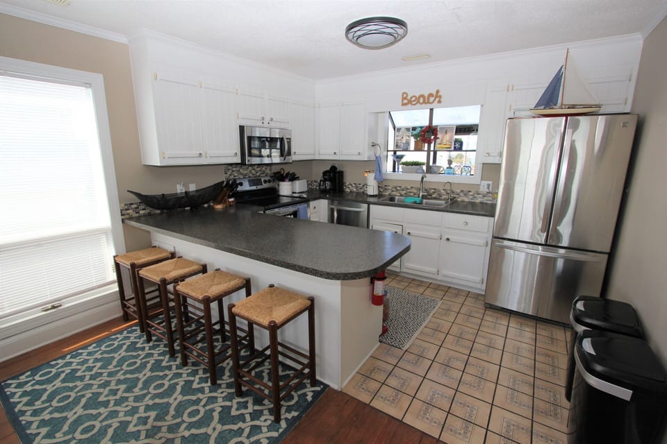 Your fully equipped coastal kitchen awaits with granite counters, bar seating, and everything needed for memorable meals.