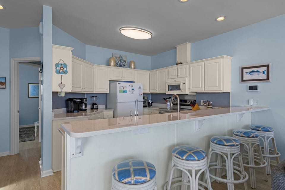 Cook and gather around this spacious kitchen featuring white cabinets, modern appliances, and a breakfast bar with coastal charm.