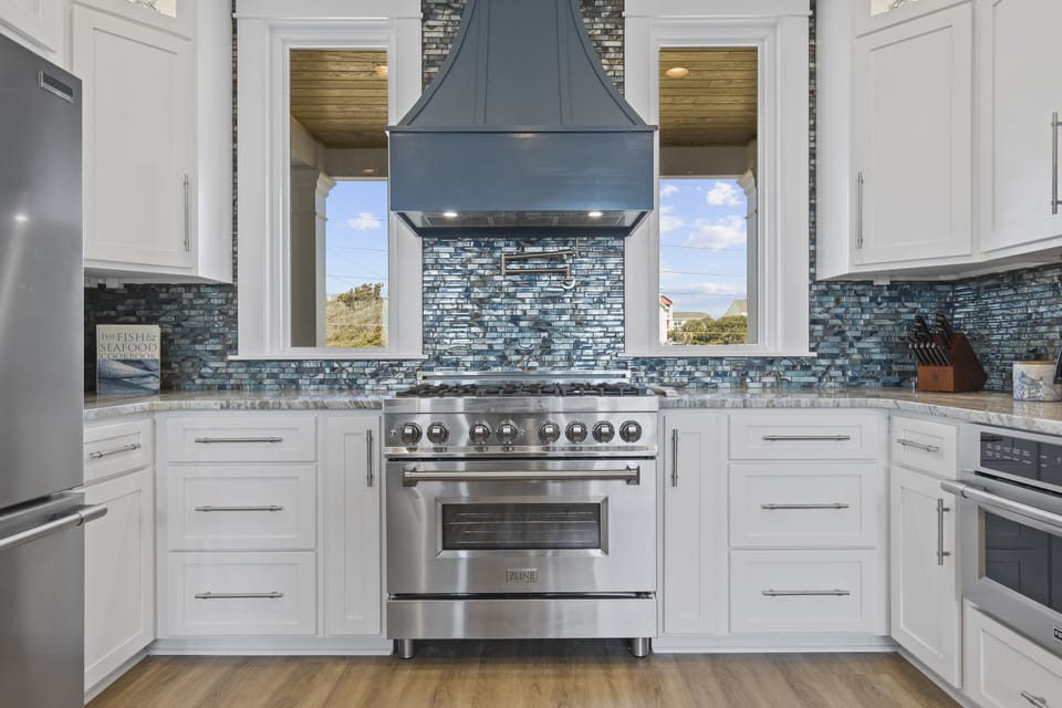 Cook gourmet meals in this stunning kitchen featuring professional-grade appliances, beautiful backsplash, and windows overlooking scenic views.