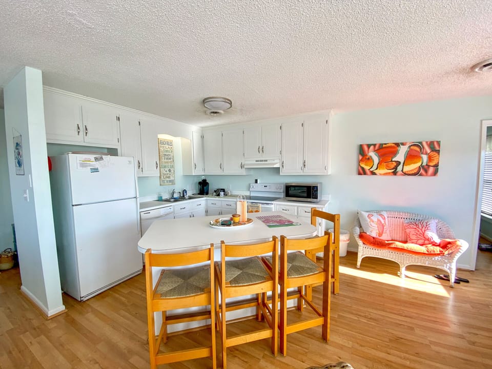 Your bright kitchen features white cabinets, full appliances, and a cozy dining nook with warm wood floors throughout.