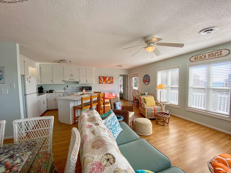Unwind in your bright, coastal-themed haven with comfy seating, full kitchen, and cheerful beach house vibes flowing throughout the open space.