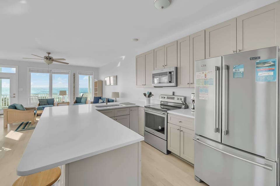Your spacious kitchen flows seamlessly into the living area, where stunning ocean views through floor-to-ceiling windows create the perfect backdrop for cooking and dining.