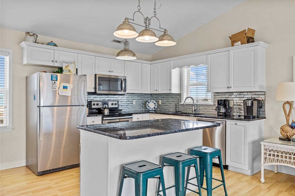 Cook your favorite meals in this bright, fully-equipped kitchen featuring stainless steel appliances, granite countertops, and stylish pendant lighting.