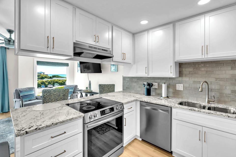 Cook in your fully-equipped modern kitchen with granite counters, stainless appliances, and serene glimpses of green lawns and sea beyond through the window.