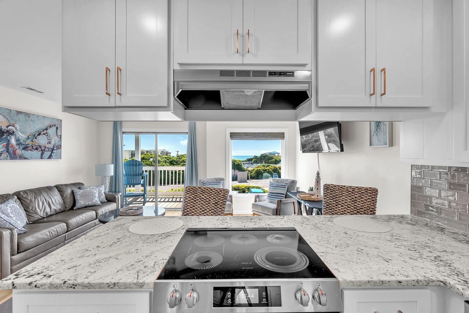 Cook your favorite meals in this sleek, open kitchen while gazing at lush greenery and blue skies through the windows, then step onto your balcony for fresh coastal air.