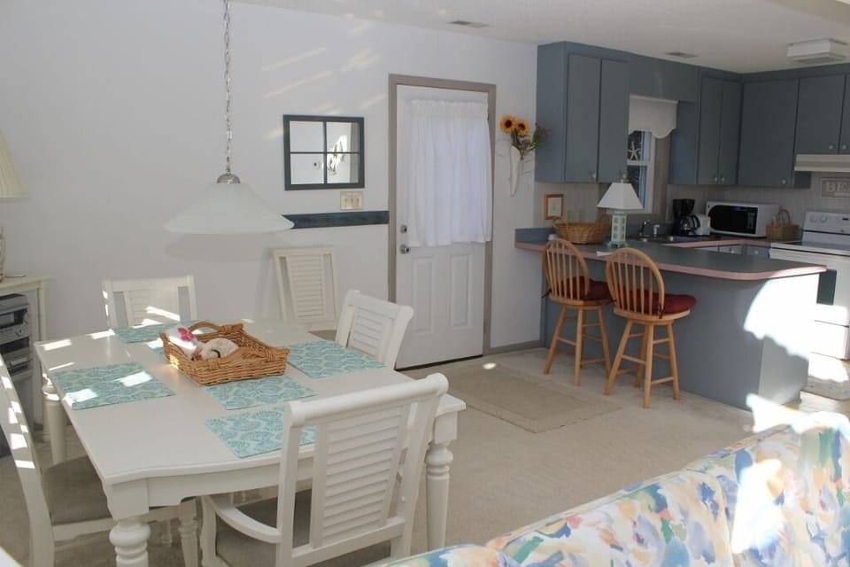 Your bright open-plan kitchen flows seamlessly into a charming dining space where morning coffee tastes better at the sunny breakfast bar.