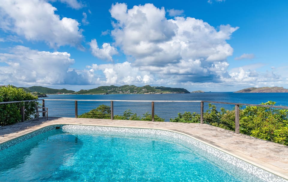 Expansive terrace, pool, lounge chairs facing the panoramic views. Gazebo with dining table next to the pool. 