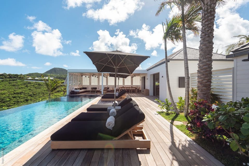 Wooden deck terrace, beautiful long heated pool, lounge chairs, 4 daybeds and a sunny seating area. 