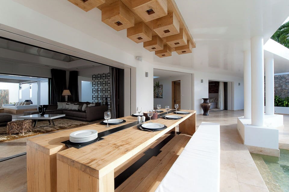 Large wooden dining table for 8 guests on the covered terrace, facing the pool and the view. 