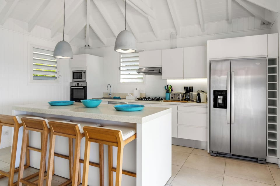 Fully-equipped kitchen, separated from the living area by a breakfast bar. Blender, coffee maker, dishwasher, freezer, ice maker, microwave, Nespresso coffee machine, oven, refrigerator, toaster. Dining table on the covered terrace, next to an outdoor lou