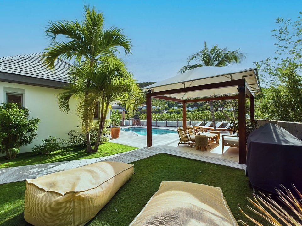 Loungers under an ajoupa next to the pool. 