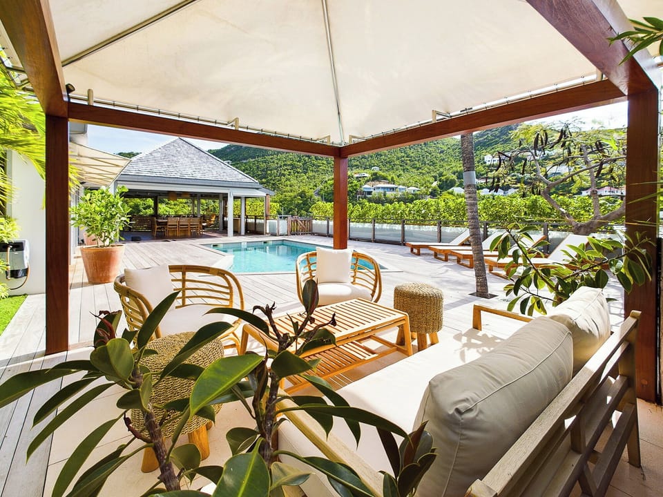 Loungers under an ajoupa next to the pool. 