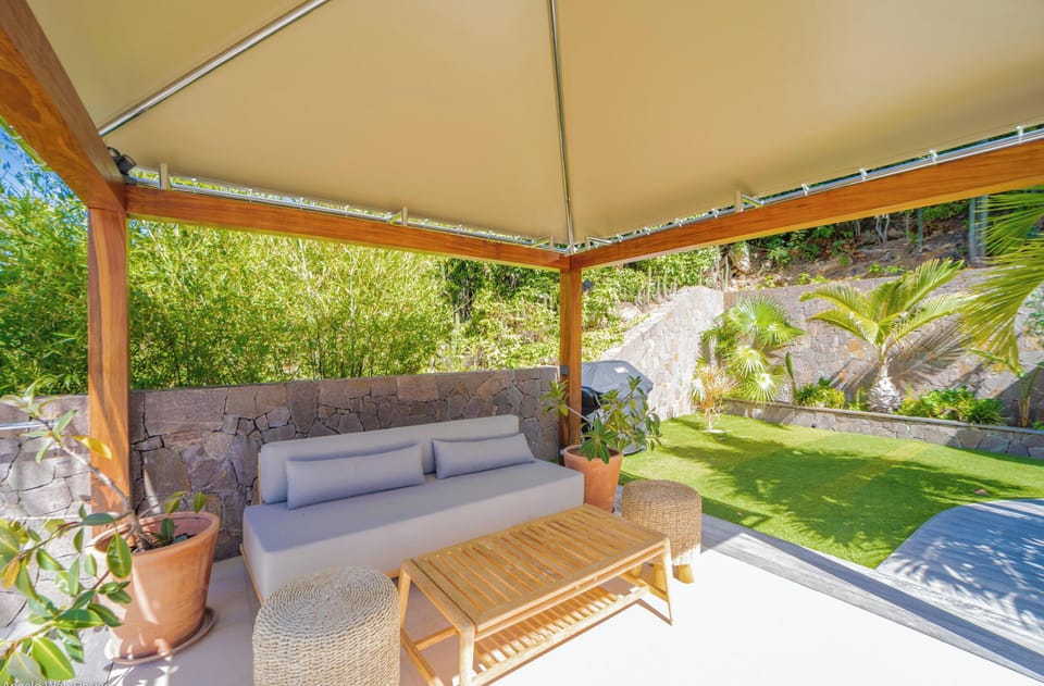 Loungers under an ajoupa next to the pool. 