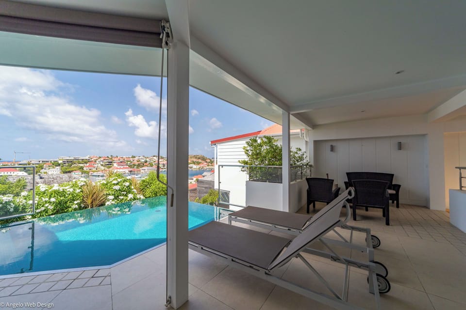 Heated pool surrounded by a large terrace with lounge chairs, Harbor view.