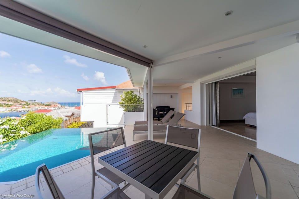 Heated pool surrounded by a large terrace with lounge chairs, Harbor view.
