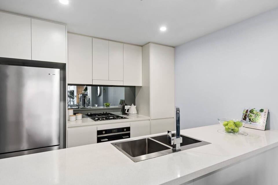 The kitchen's wide island stretches across the room providing ample stone bench space for easy meal prep. Dual sinks make cleaning up a breeze too. 
