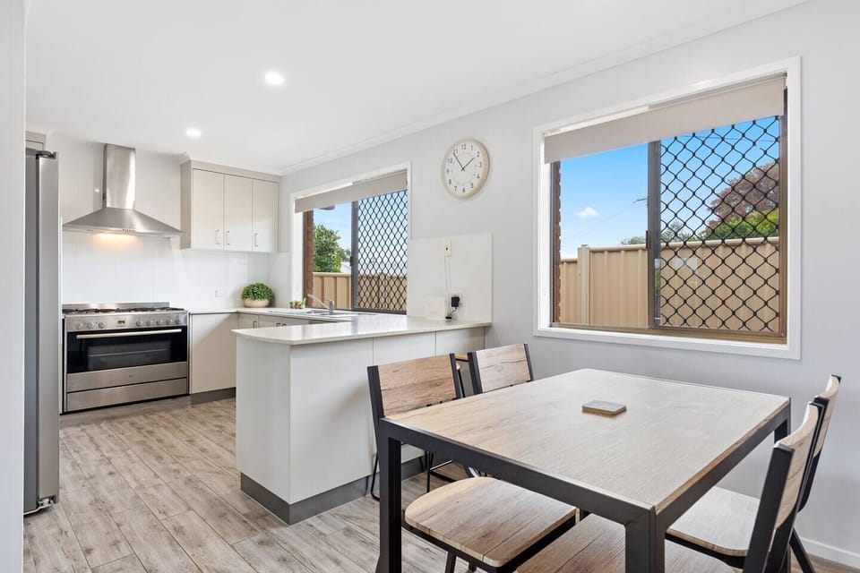 The light-filled dining space offers stools at the breakfast bar and a four-seater table setting. 
