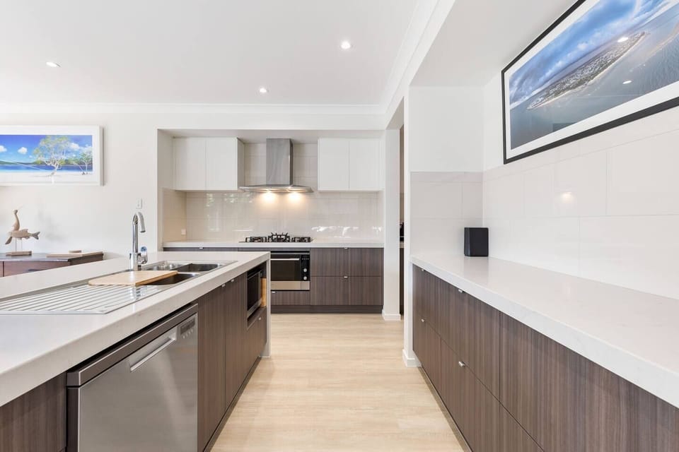 Cook everything from quick breakfasts to family feasts in the contemporary kitchen, where a gas cooktop, wide oven, coffee machine and handy appliances are complemented by a dishwasher and dual sink for easy clean-up.