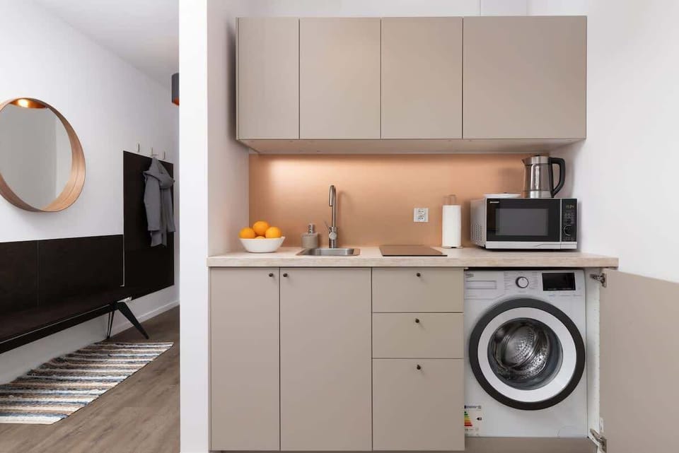 A kitchen view featuring beige cabinets, a washing machine, and warm under-cabinet lighting.

