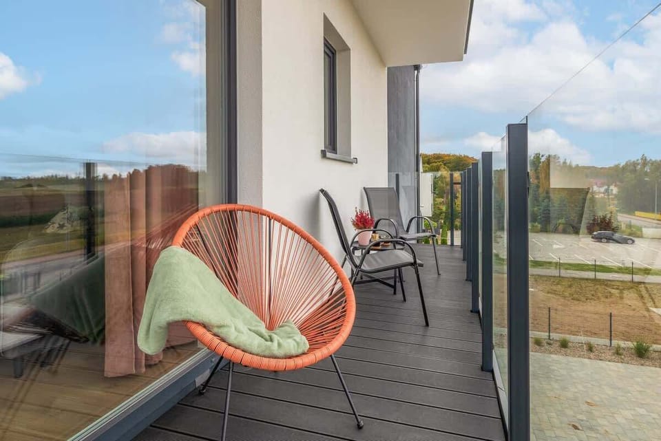 Another balcony view featuring a hanging chair and a glass railing with a scenic background.
