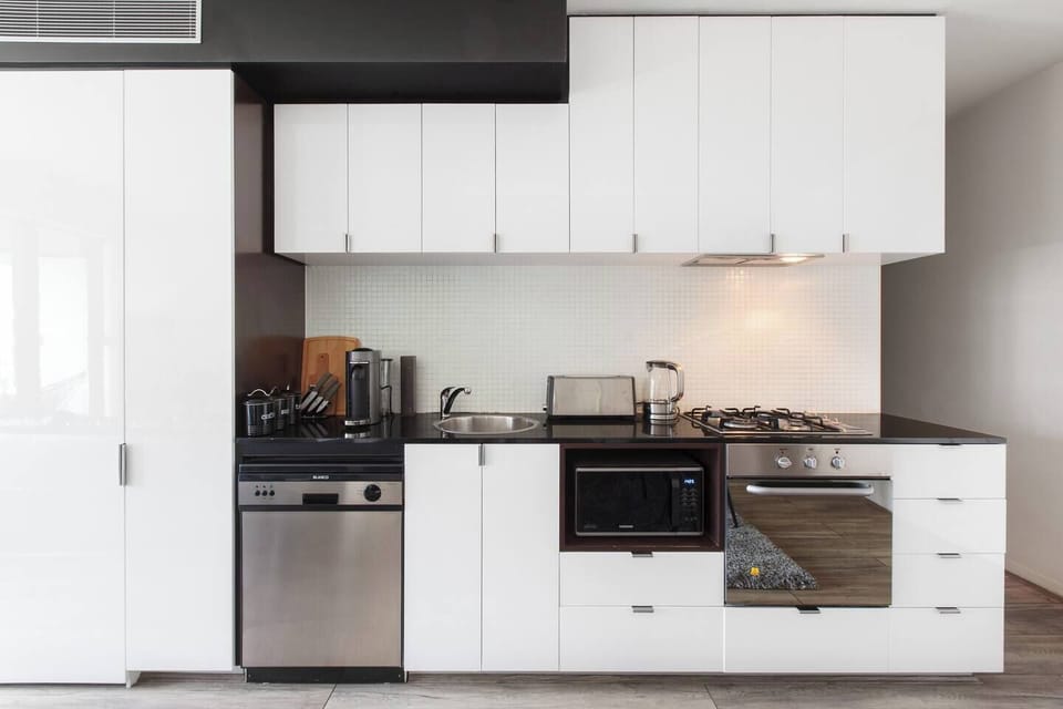 A contemporary kitchen lines the back wall and is fully equipped with modern appliances including a fridge, microwave, gas stove, oven and dishwasher