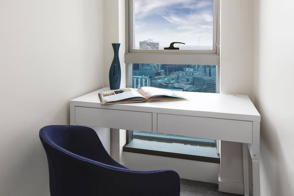 The main bedroom also offers a dedicated working space with a desk and a chair, and stunning city views